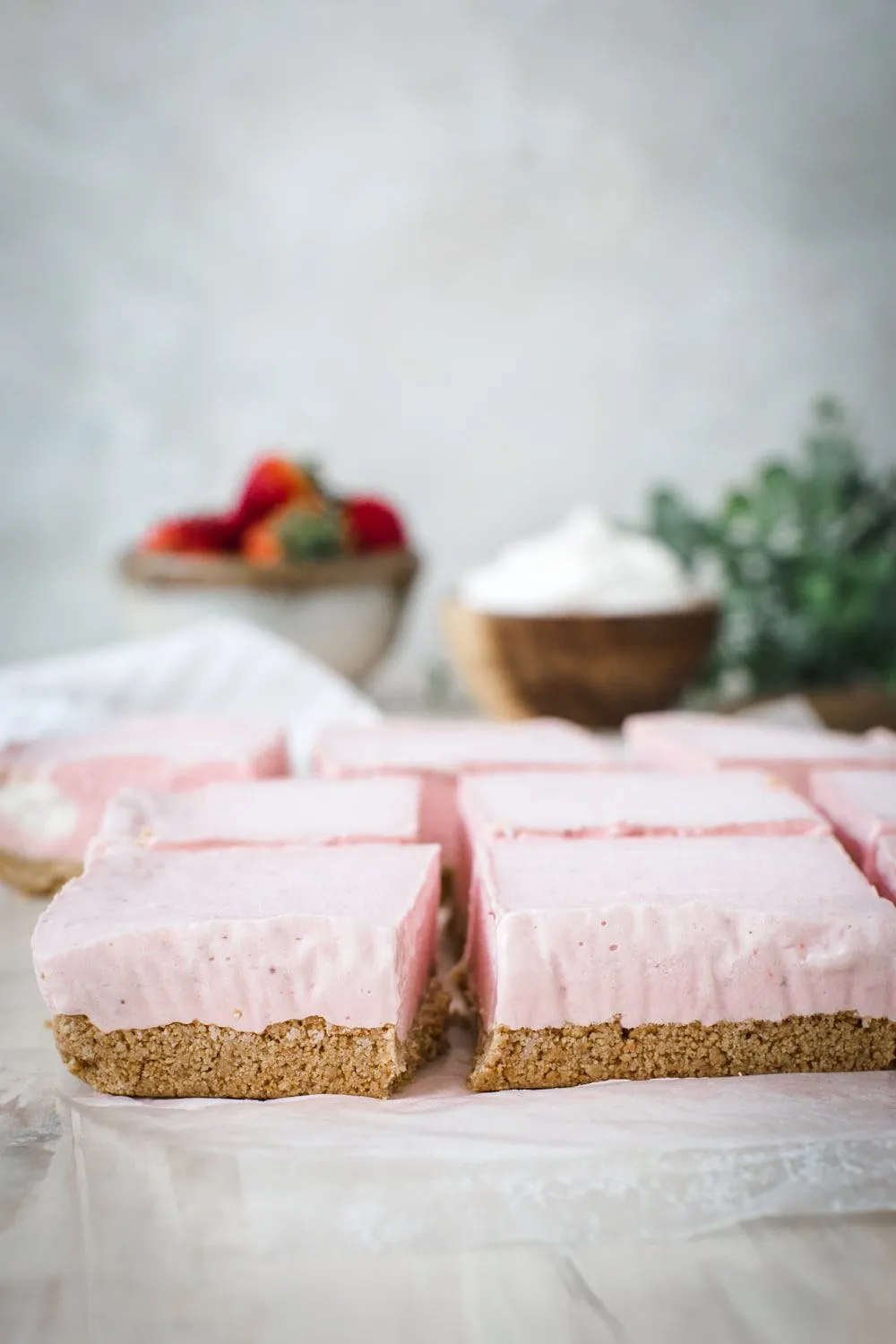 strawberry cheesecake sliced into squares on parchment paper