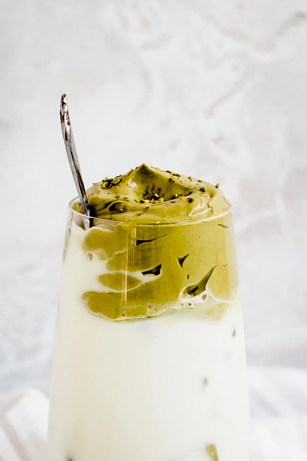 Dalgona matcha whip on top of iced milk in glass.