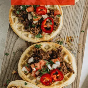 Waffle tacos on wooden cutting board with pico de gallo.