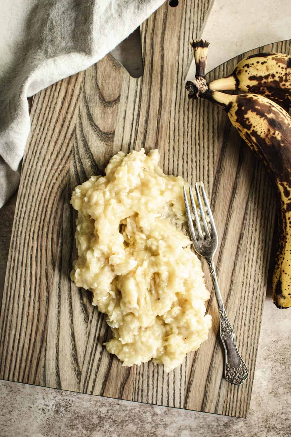 Mashed bananas on a wooden cutting board.