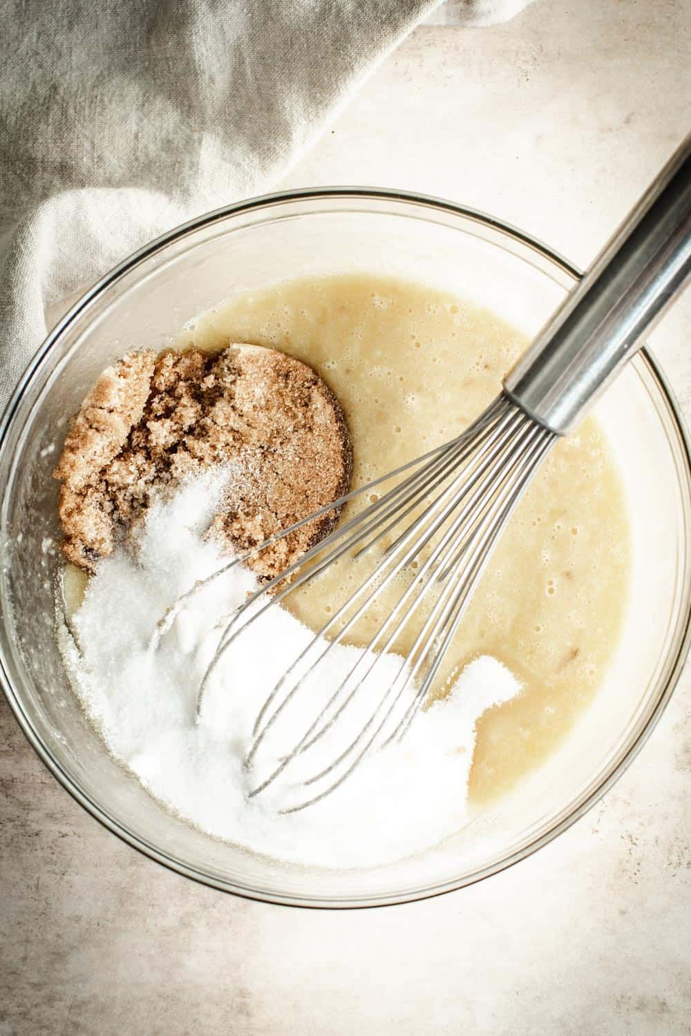 Banana bread batter in mixing bowl with wire whisk.
