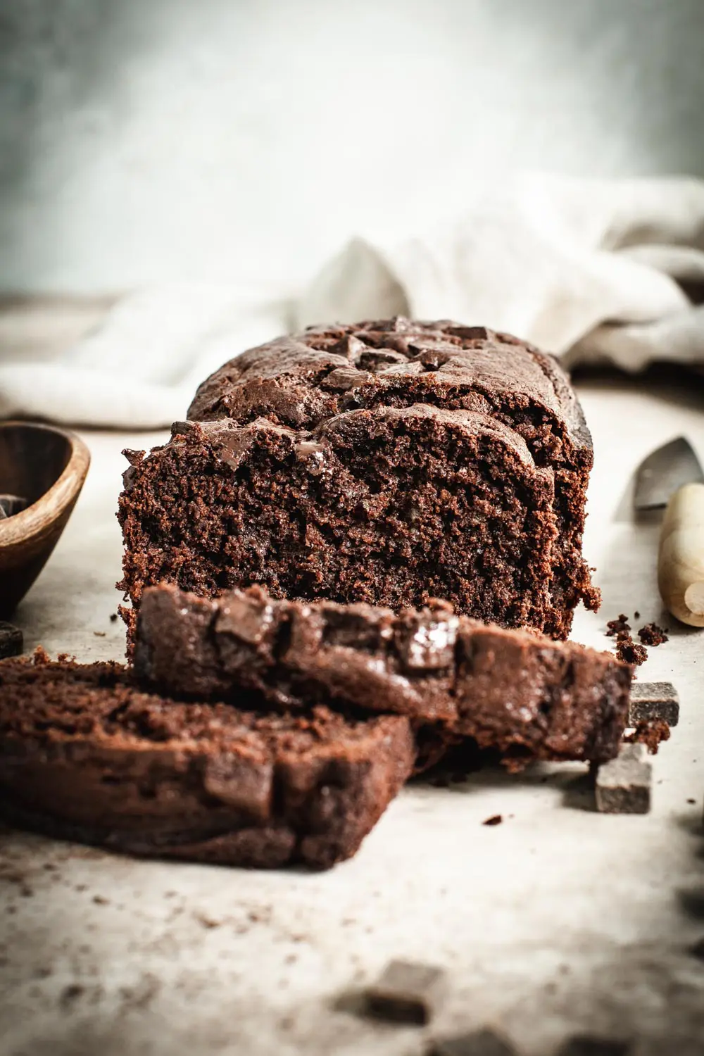 Sliced chocolate banana bread with loaf in background.