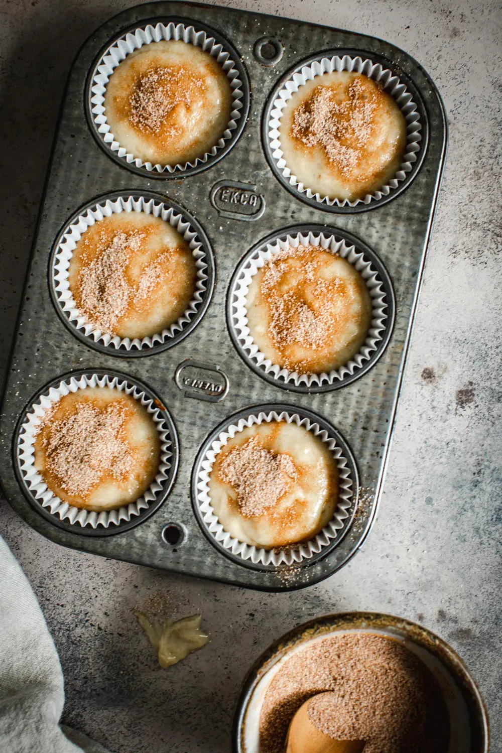Cinnamon sugar banana muffin batter in muffin cups in a muffin tin.