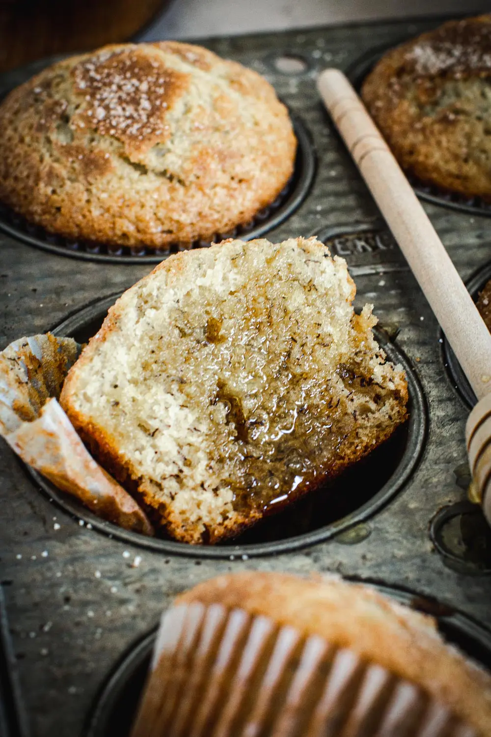 Torn cinnamon sugar banana muffin in a muffin tin.