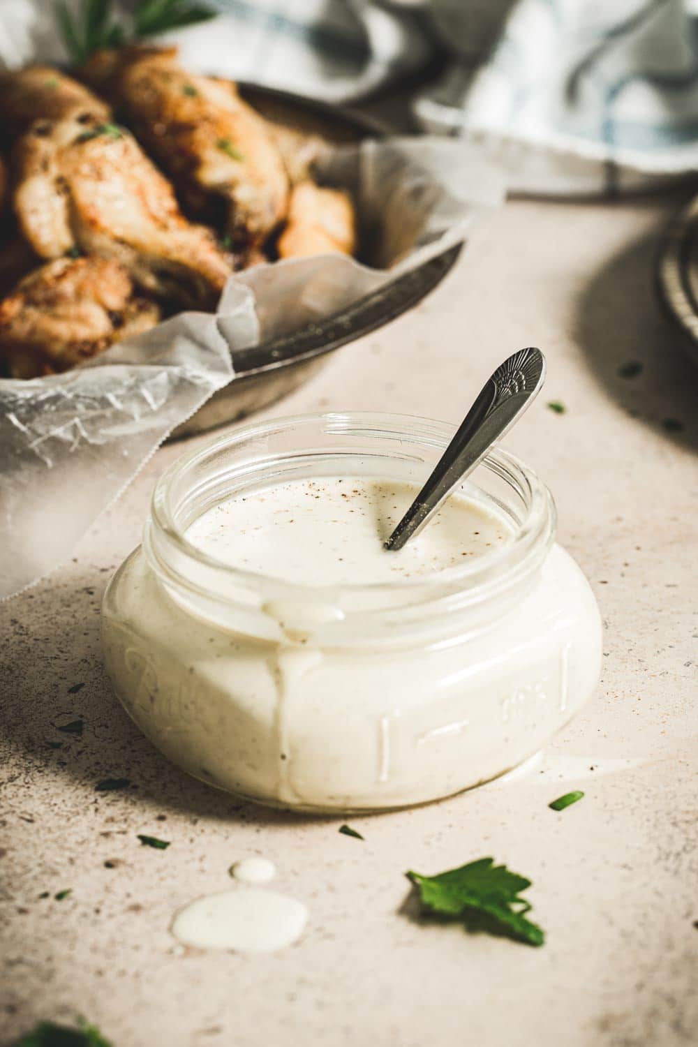 White sauce in small glass jar with silver spoon.