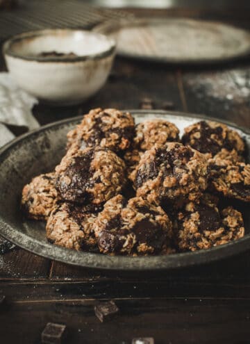 Oatmeal cookies in metal pie tin on wooden table.