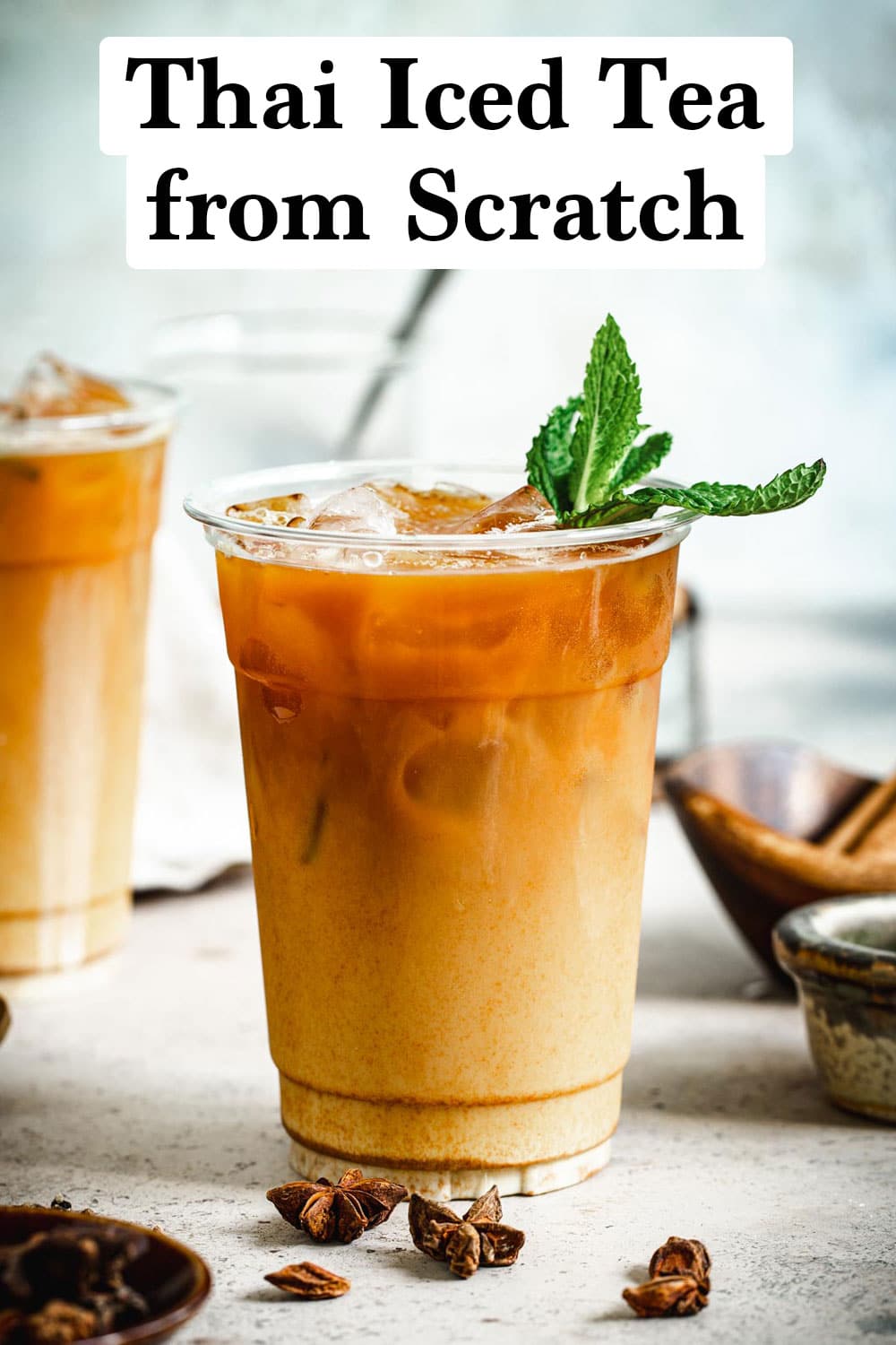 Thai iced tea from scratch in a plastic cup topped with mint leaves.