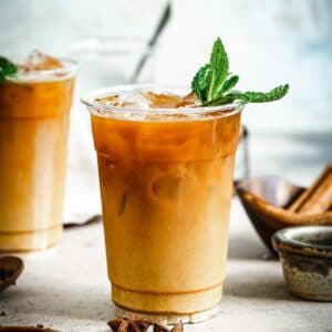 Thai iced tea topped with mint leaves in a plastic cup.