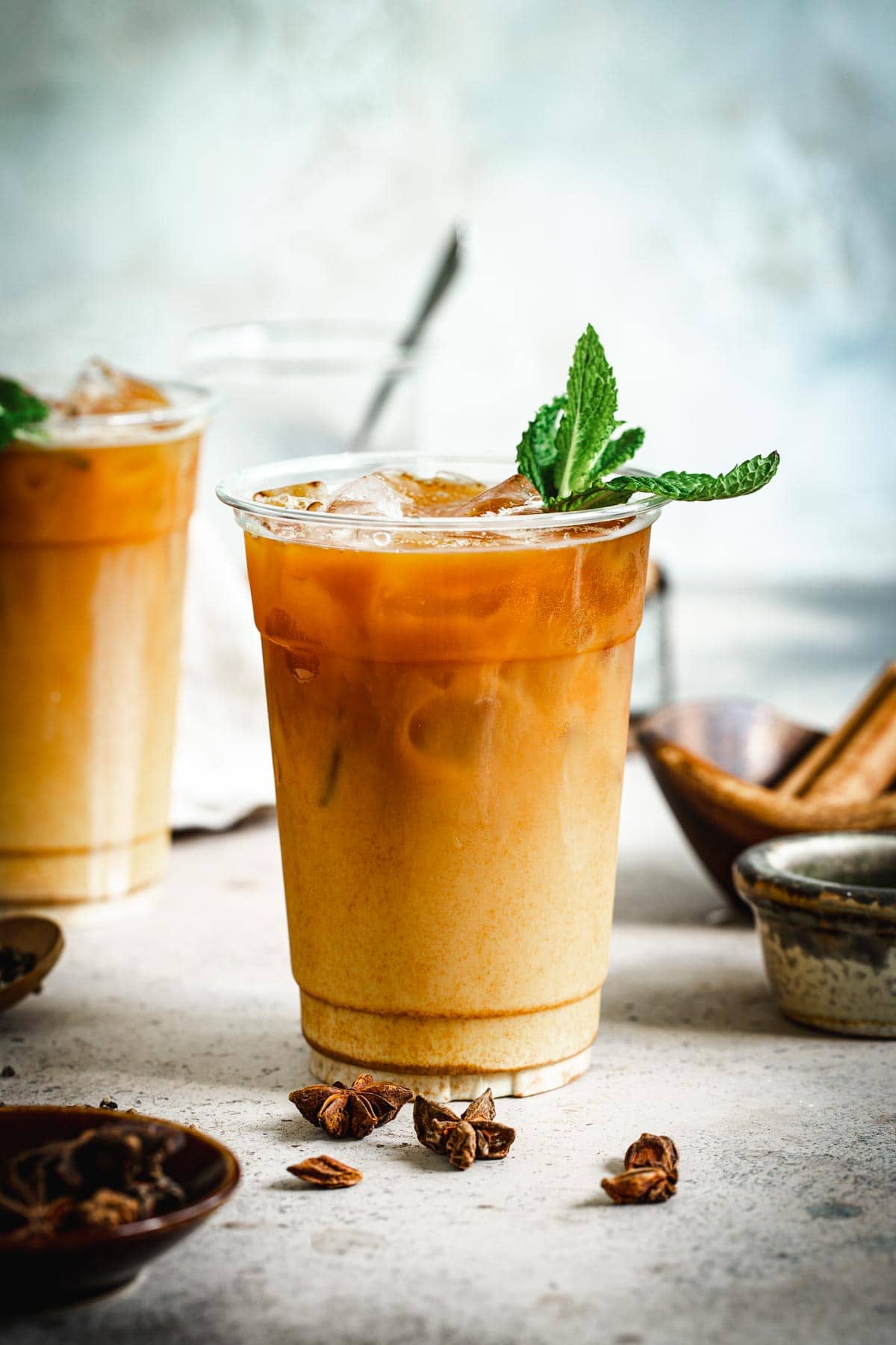 Thai iced tea topped with mint leaves in a plastic cup.