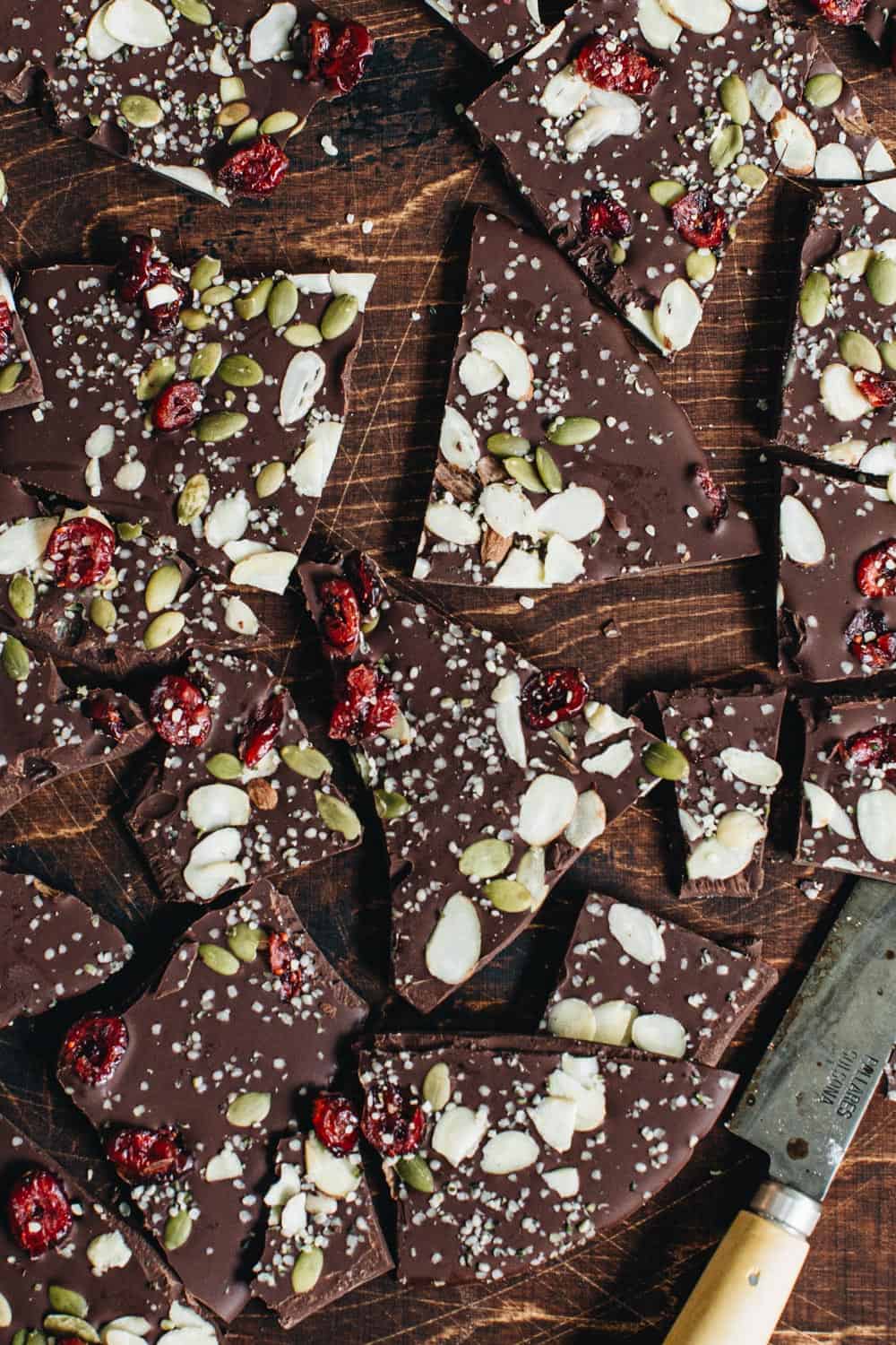 Healthy chocolate bark broken into pieces on a wooden board.