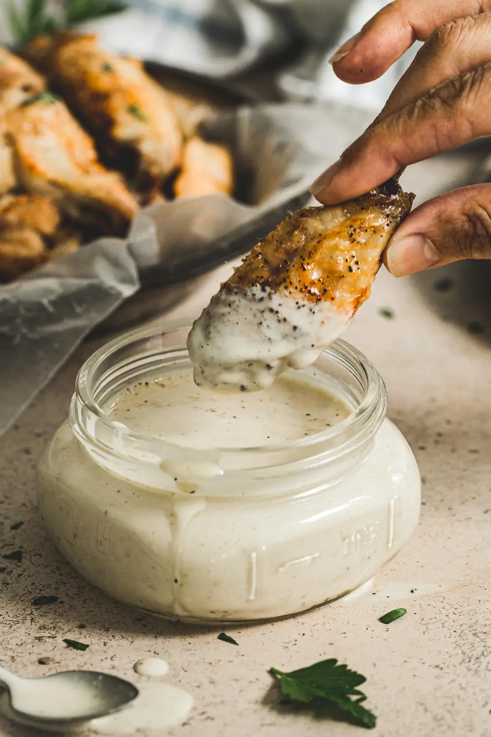 Chicken wing dipping into Alabama white sauce.