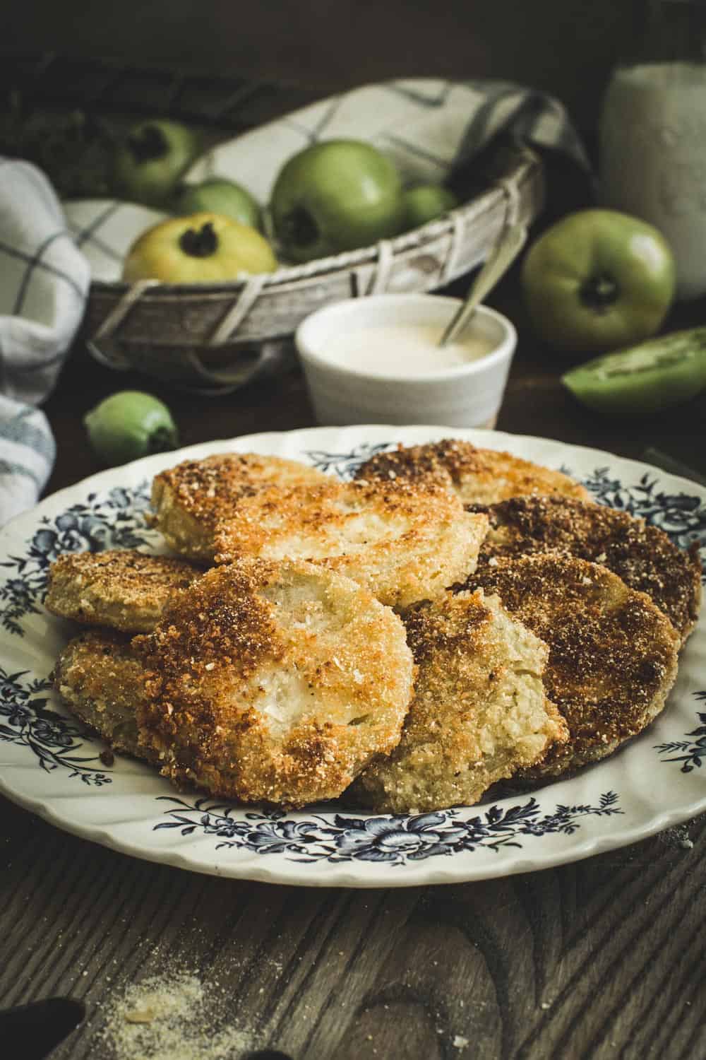 fried green tomatoes spread on large plate with blue flower design and white dipping sauce in background