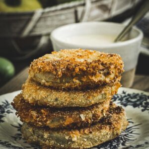 Fried green tomatoes stacked on a blue and white plate.