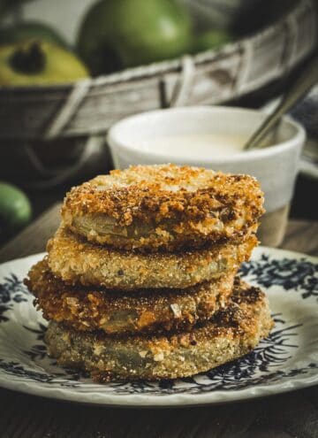 Fried green tomatoes stacked on a blue and white plate.