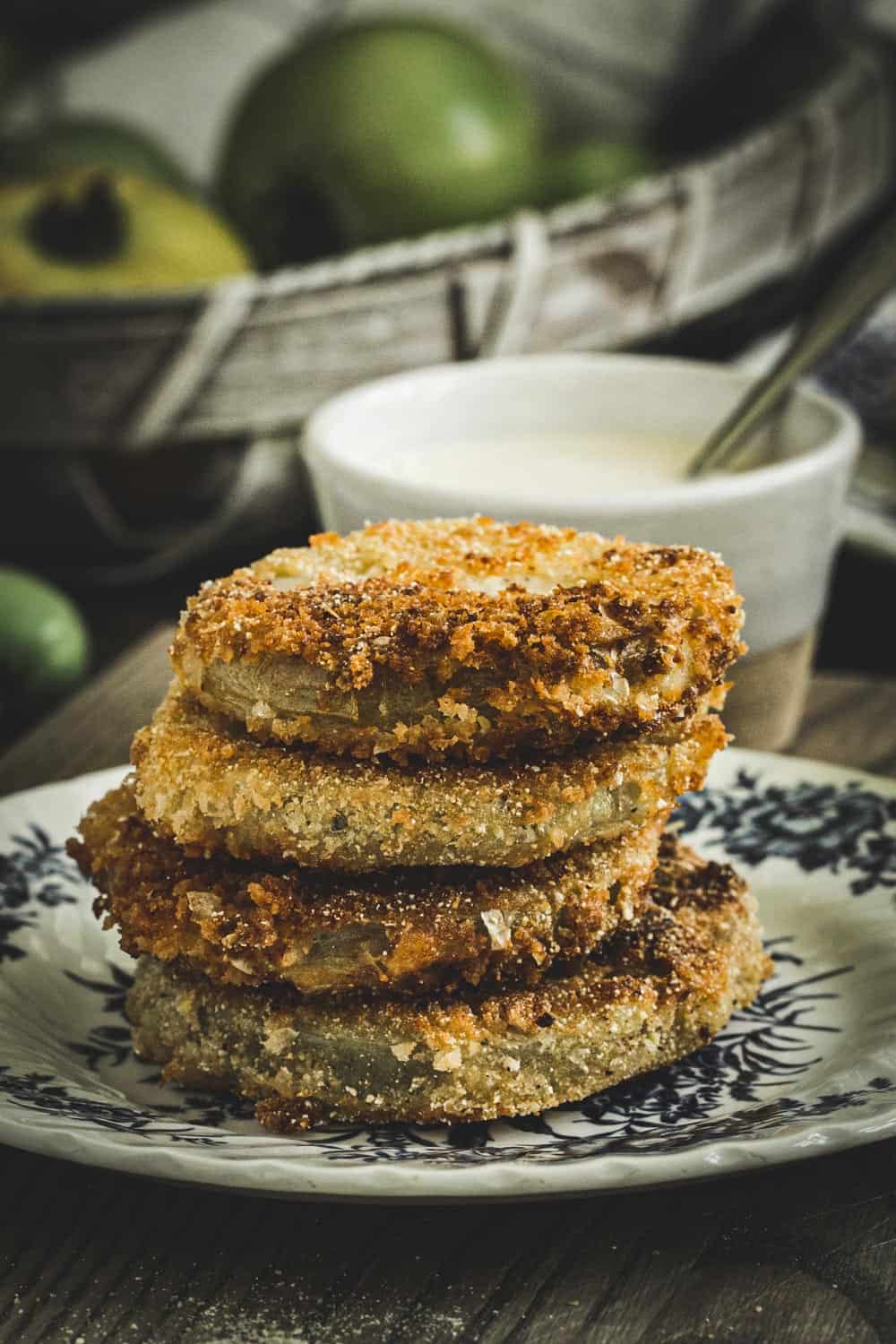 Fried green tomatoes stacked on a blue and white plate.