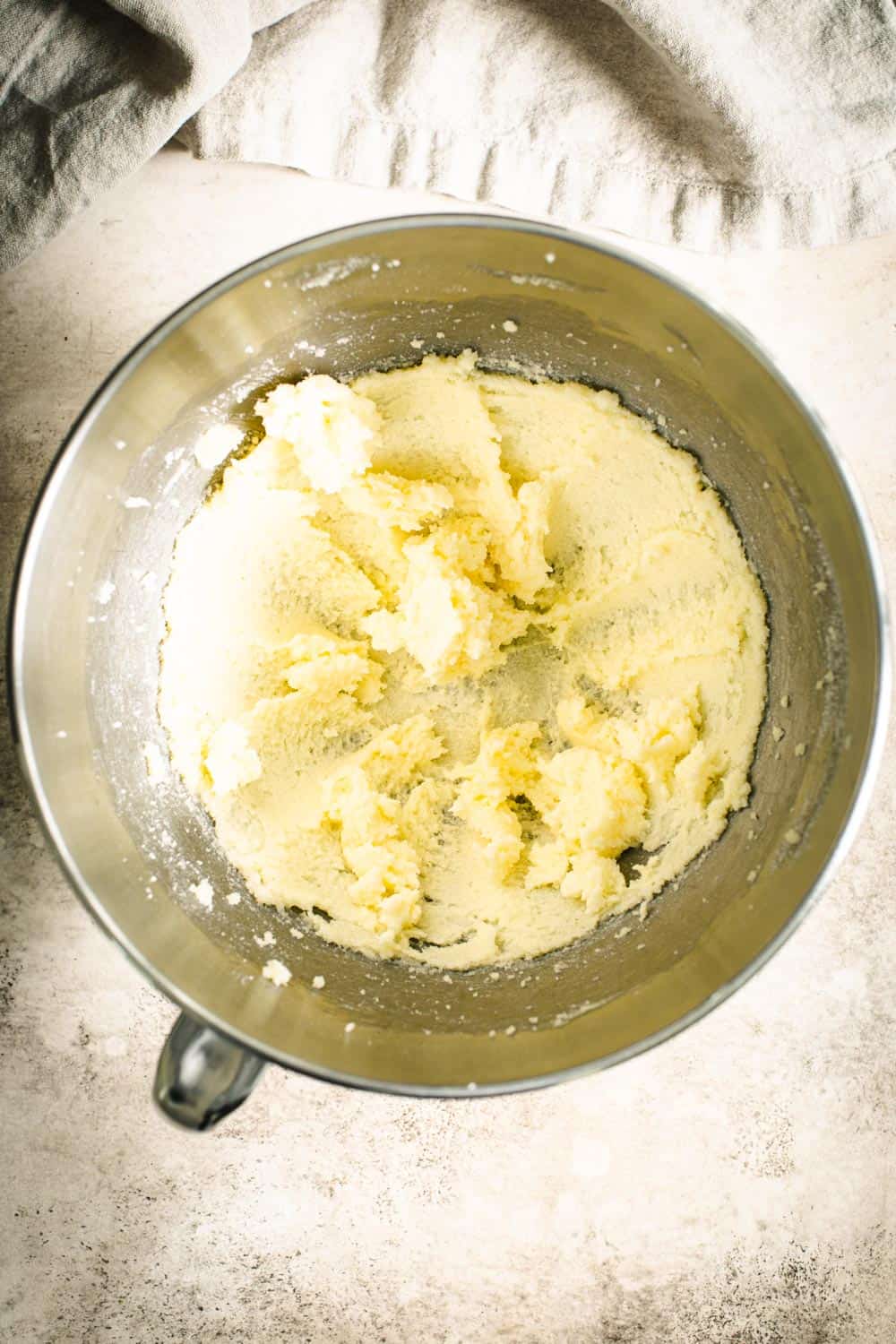 Beaten butter and sugar in a silver mixing bowl.