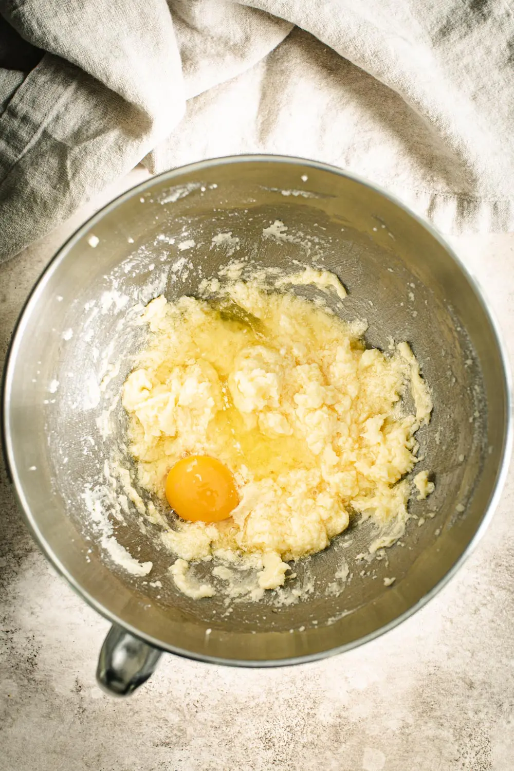 Egg in torte batter in a silver mixing bowl.