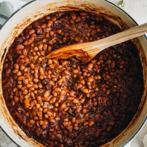 slow cooked baked beans in a large Dutch oven with wooden spoon