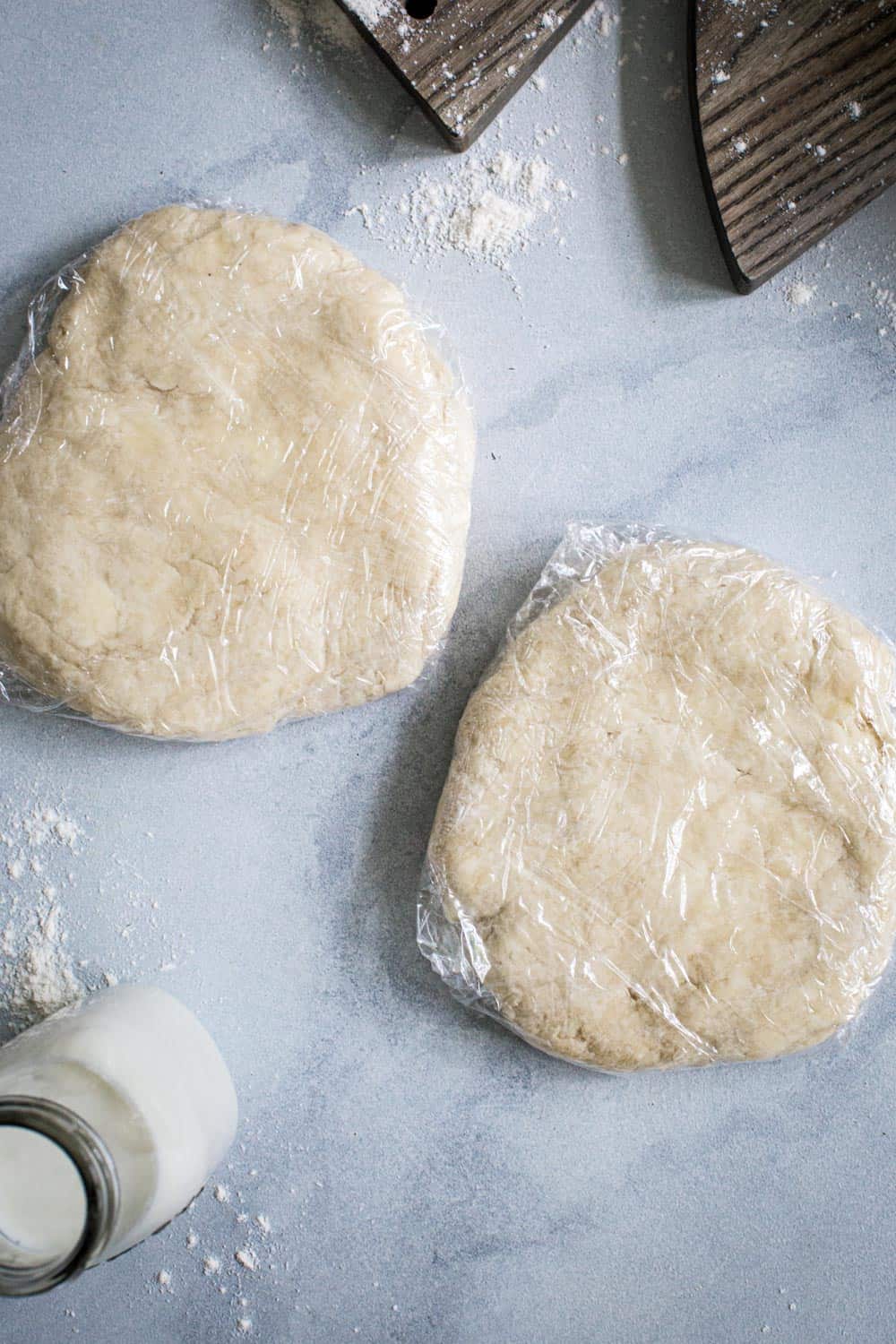 Two discs of pie dough wrapped in plastic wrap.