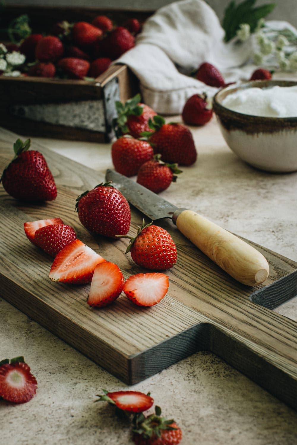 sliced strawberries on wooden cutting board with knife