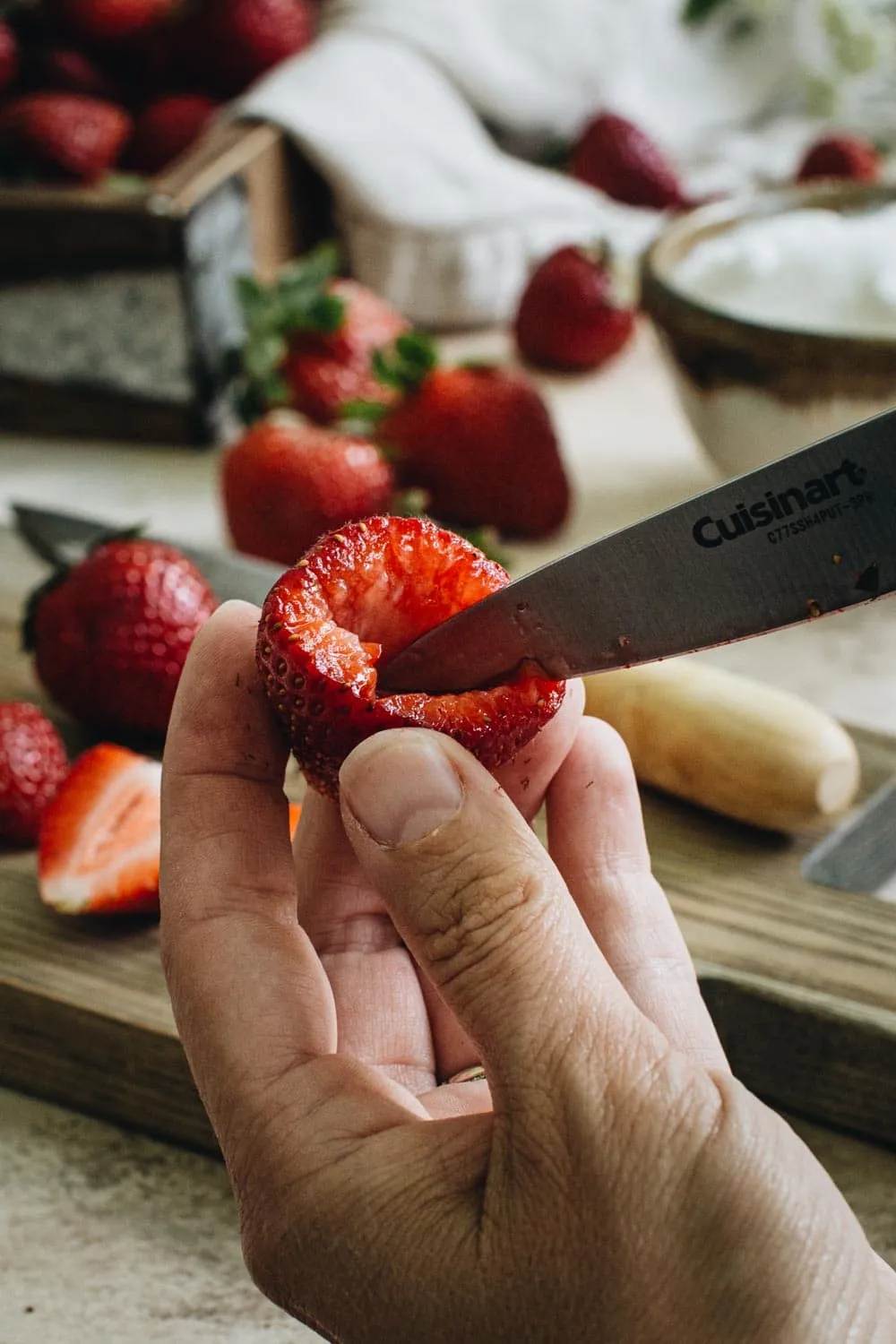 hand holding a strawberry with a knife