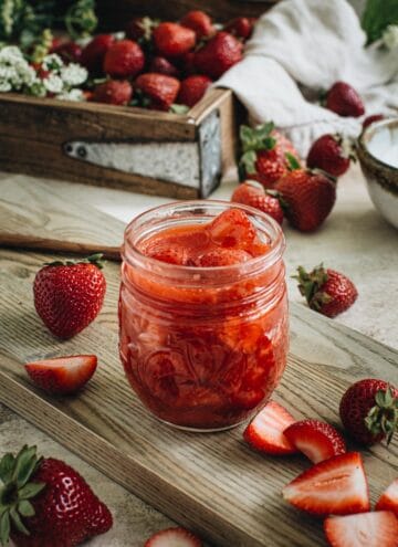 vegan strawberry sauce in glass container on wooden cutting board