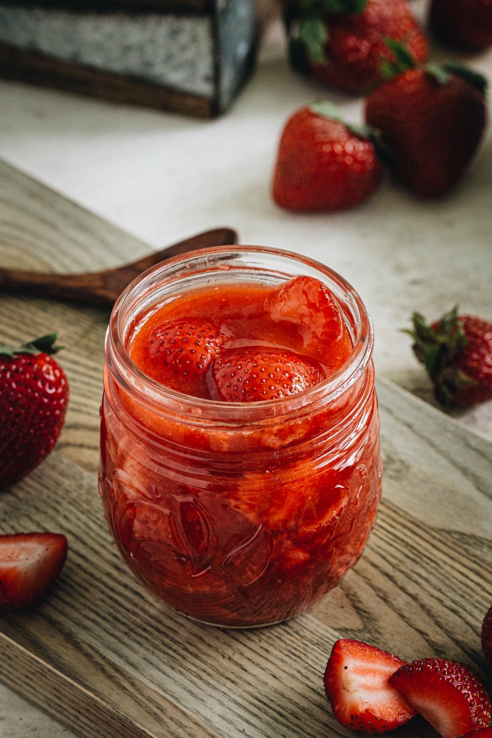 strawberry sauce in glass jar on wood cutting board