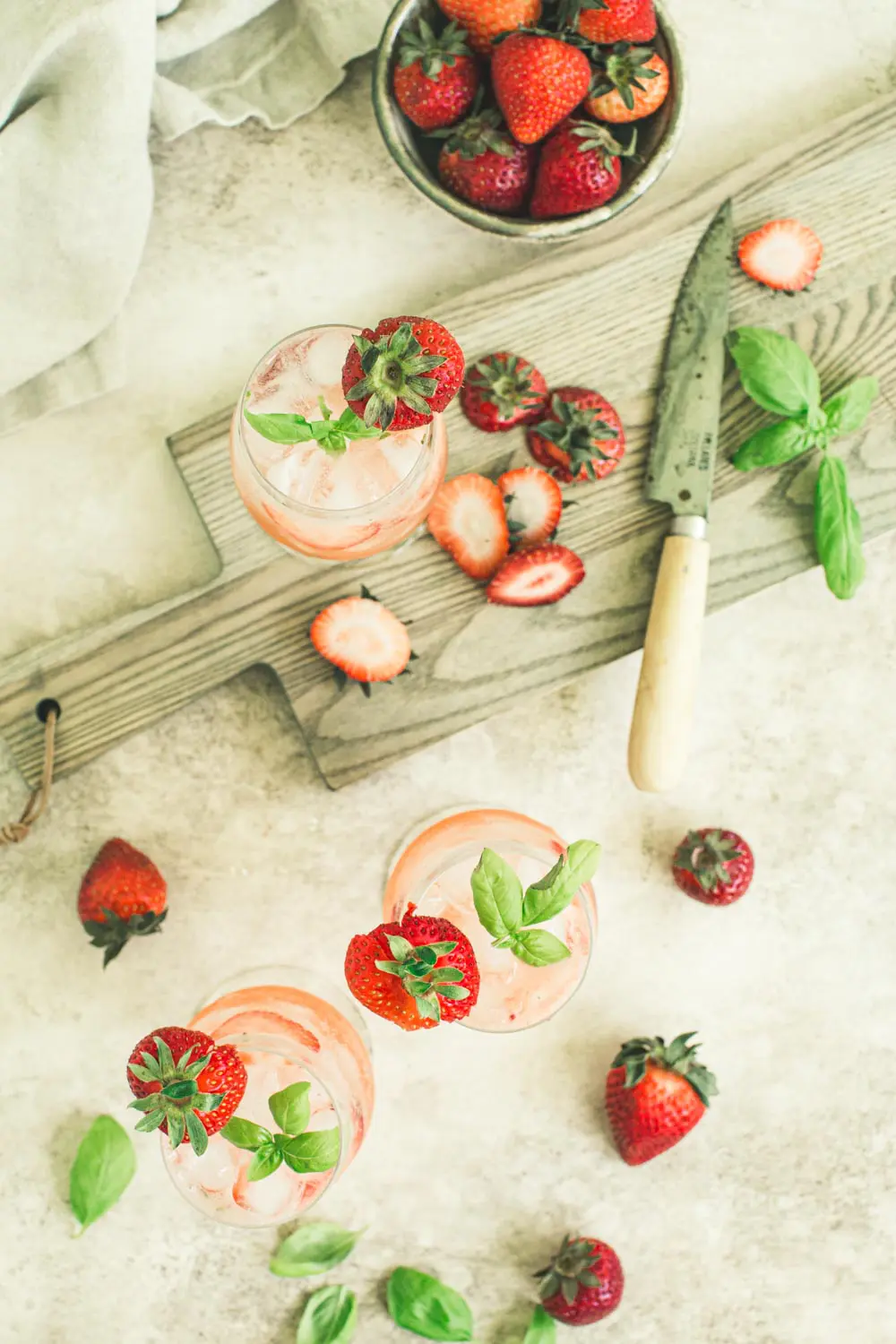 Top view of strawberry basil mojitos with sliced strawberries surrounding.