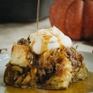 Square slice of french toast casserole with whipped cream and syrup being poured on top.