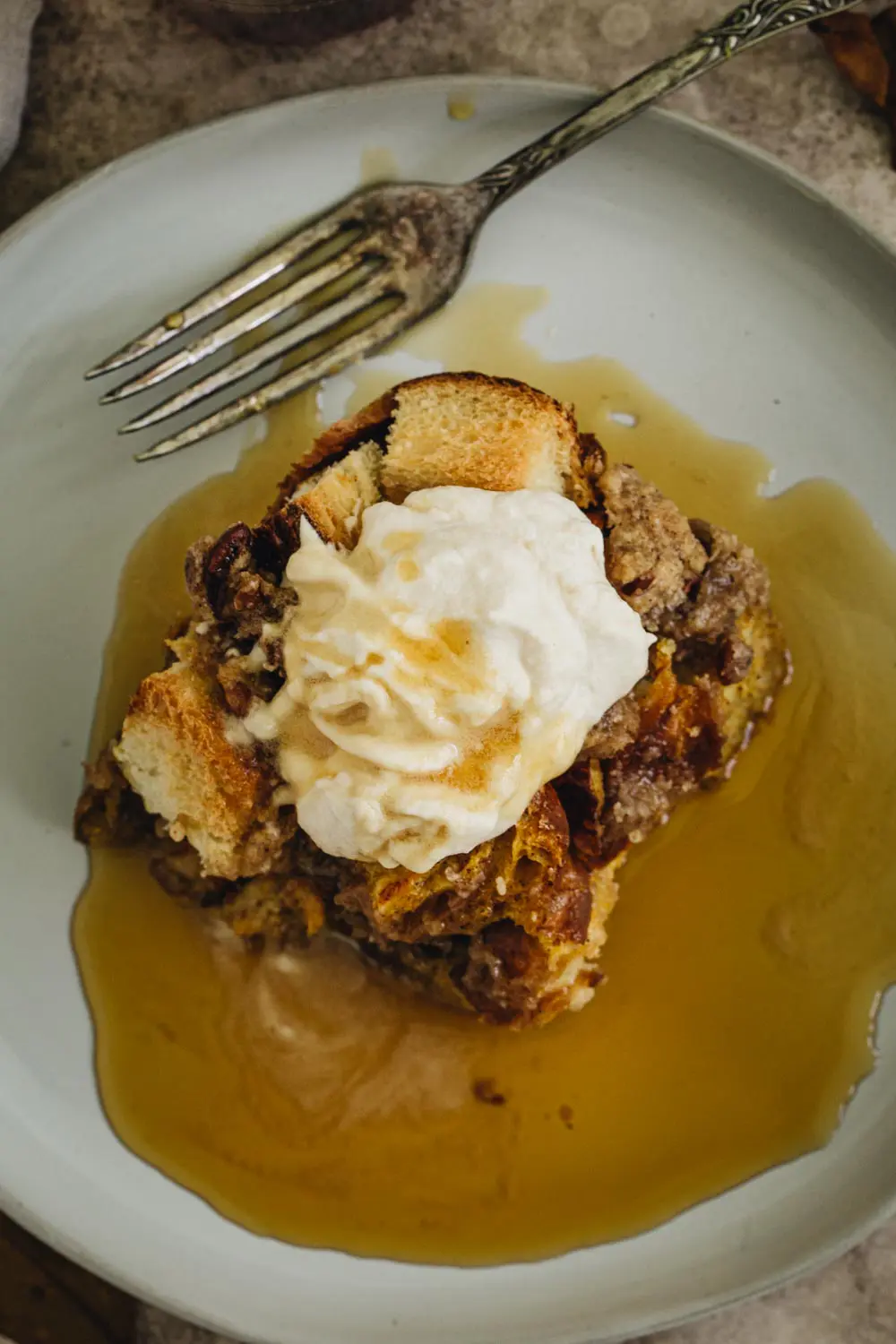 Pumpkin french toast casserole on a plate topped with whipped cream and syrup.