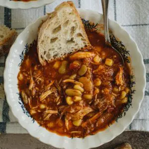 Alabama Campe Stew in a soup bowl with silver spoon and white slice of bread in it.