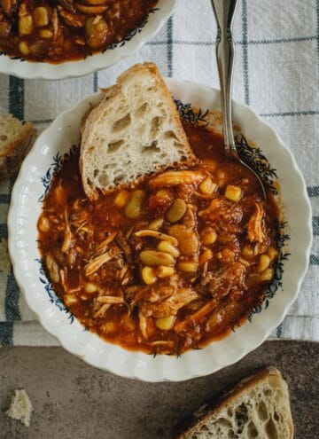 Alabama Campe Stew in a soup bowl with silver spoon and white slice of bread in it.