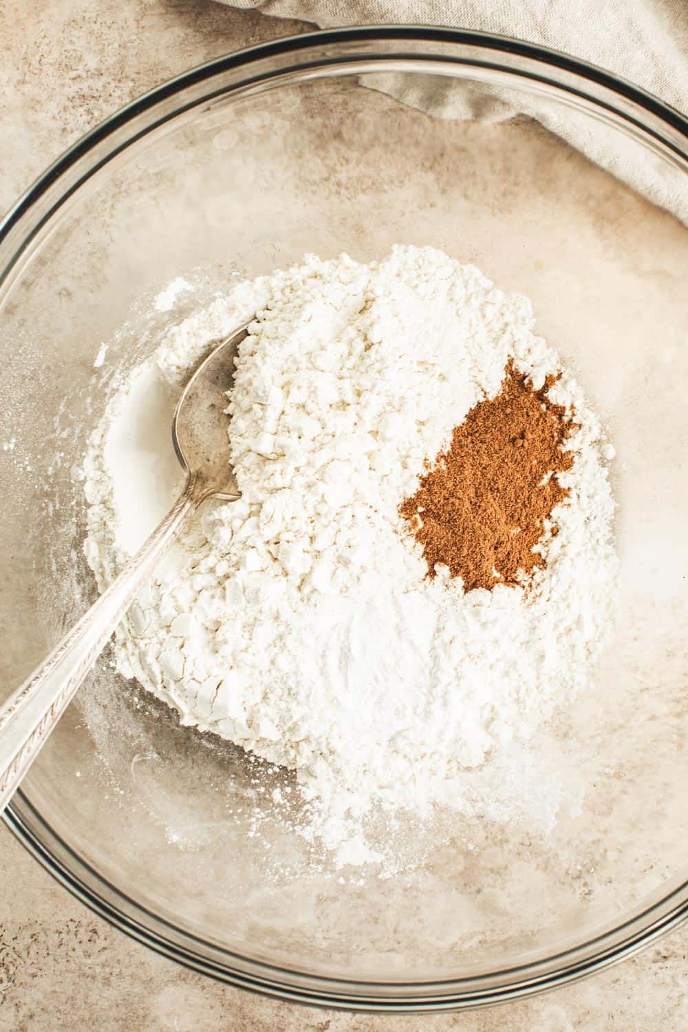 Mixing dry ingredients for healthy pumpkin pancakes in a glass bowl.