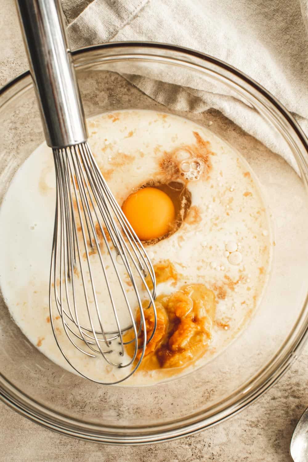 Wet ingredients for pumpkin pancakes in glass bowl.