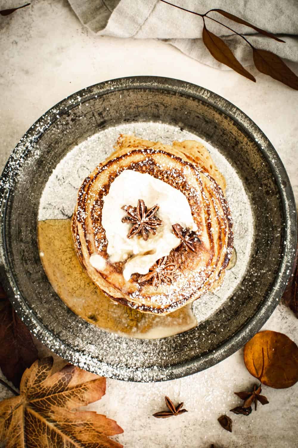 Top view of pumpkin pancakes with whipped cream and sprinkled with powdered sugar.
