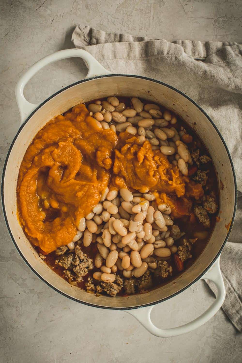 Adding the pumpkin and white beans to the chili.