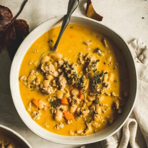 Turkey Pumpkin White Bean Chili in white bowl with a silver spoon.