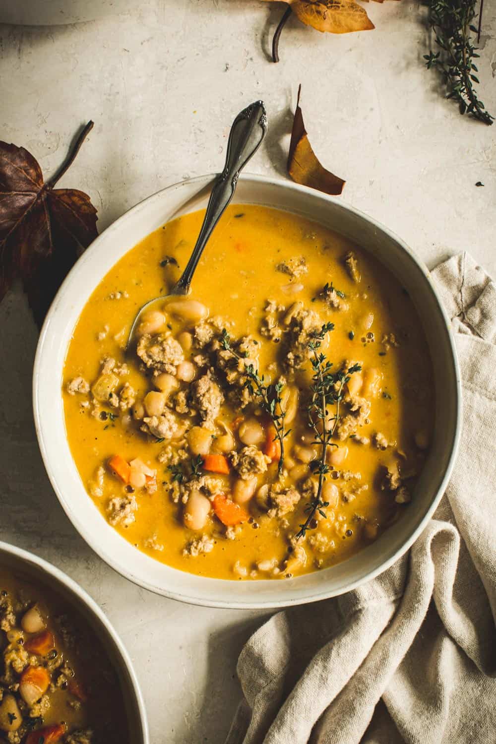 Turkey Pumpkin White Bean Chili in white bowl with a silver spoon.