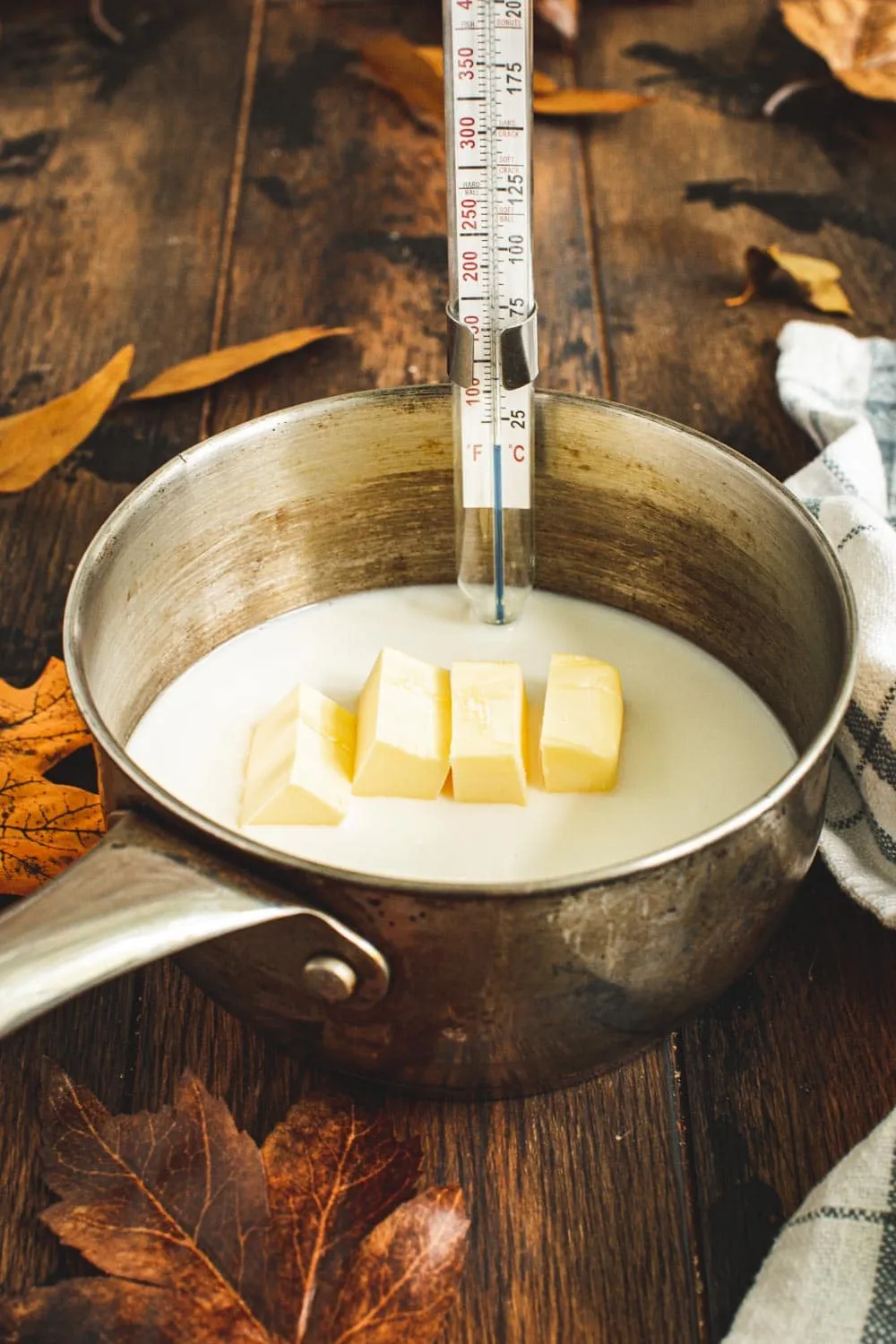 Milk mixture ingredients in small saucepan with candy thermometer clipped to the side.