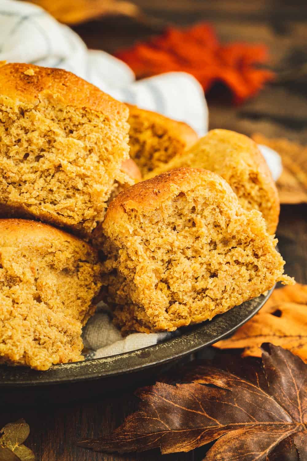 Pumpkin rolls stacked in a metal tin on a wooden table.