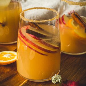 Glass of caramel apple sangria with a caramel and sugar coated rim.