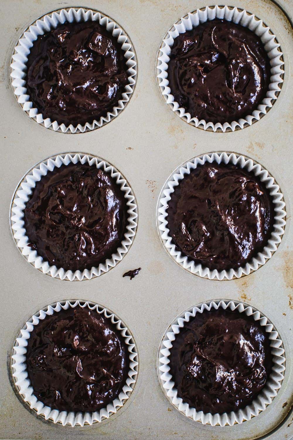 Chocolate muffin batter in muffin tin.