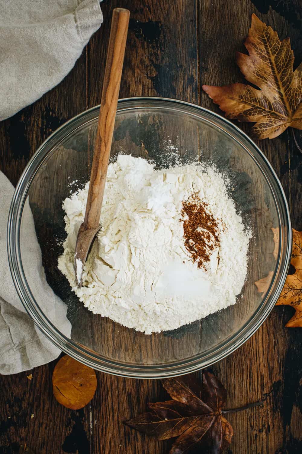Dry ingredients for chocolate and pumpkin brownies in a mixing bowl with a wooden spoon.