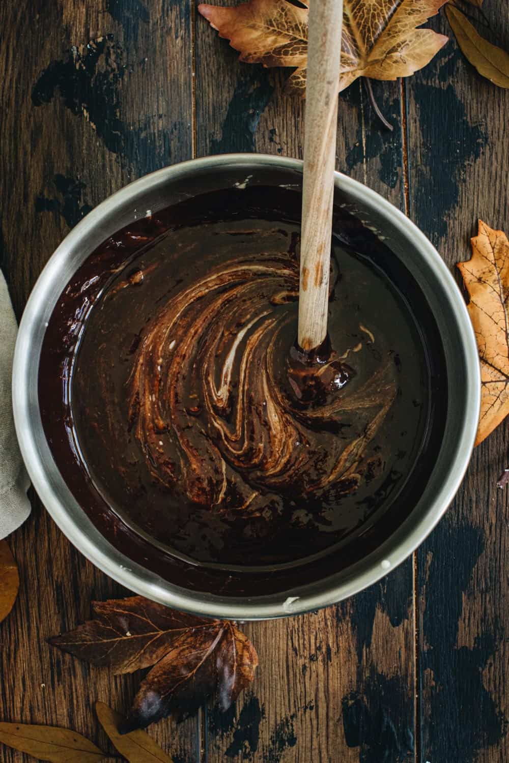 Chocolate batter for pumpkin swirl brownies in a silver mixing bowl.