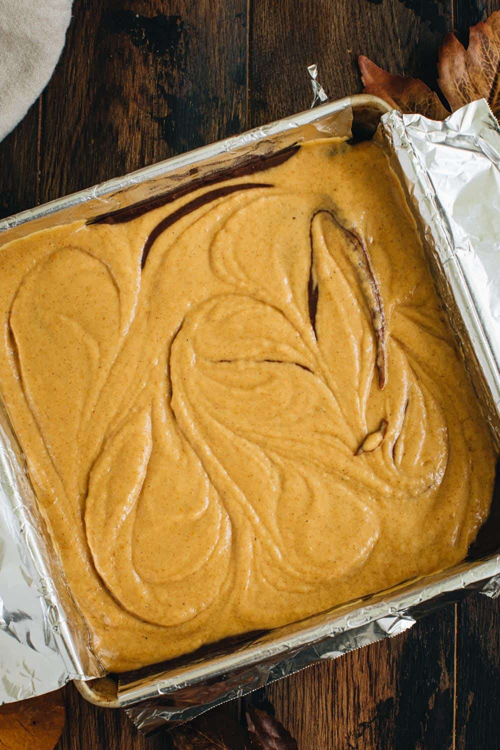 Pumpkin brownie batter in a square baking pan.