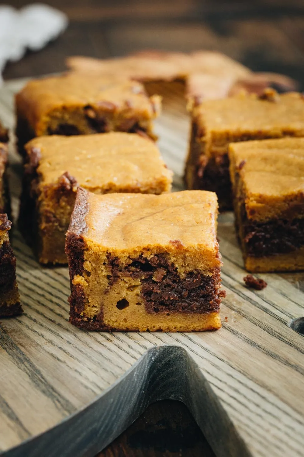 Pumpkin swirl brownies sitting on a wooden cutting board.