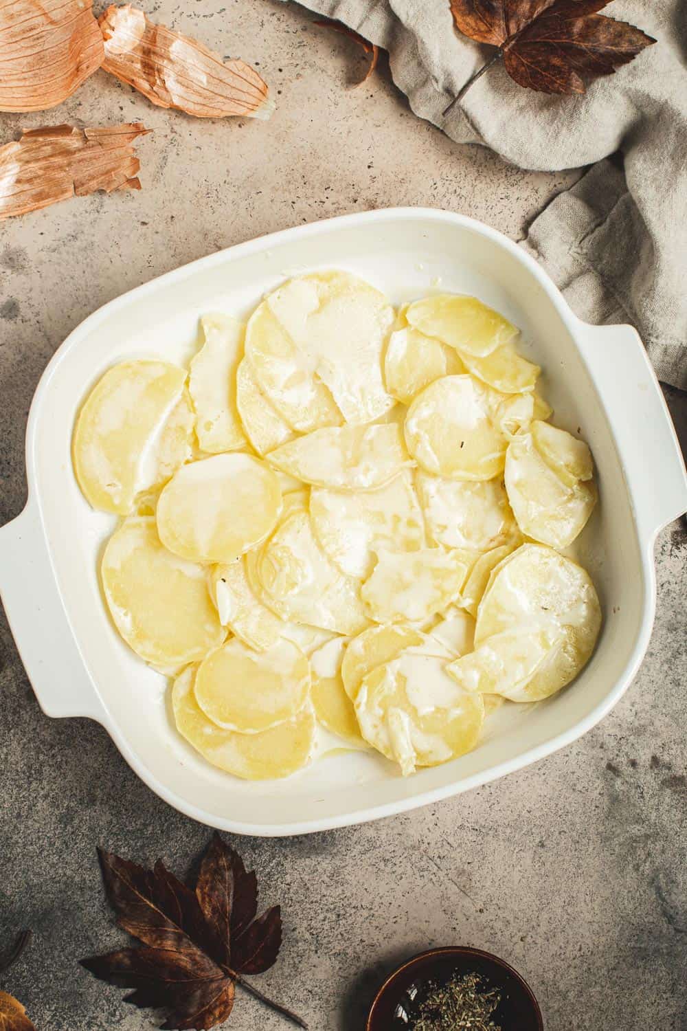 Sliced potatoes in a square baking dish.