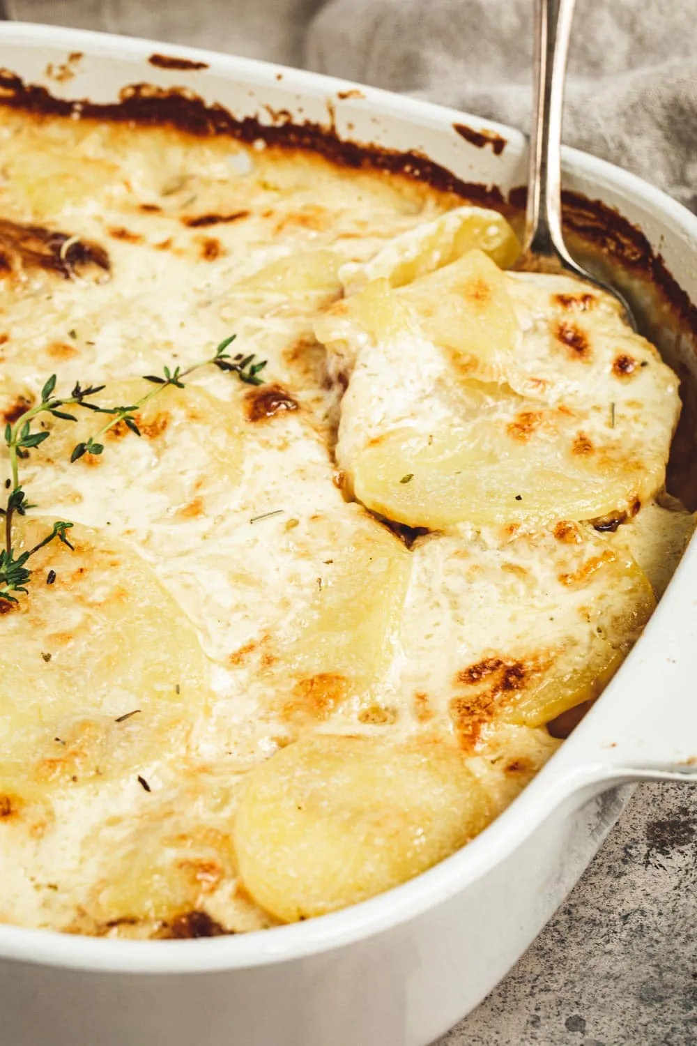 Spoon scooping out scalloped potatoes with caramelized onions.