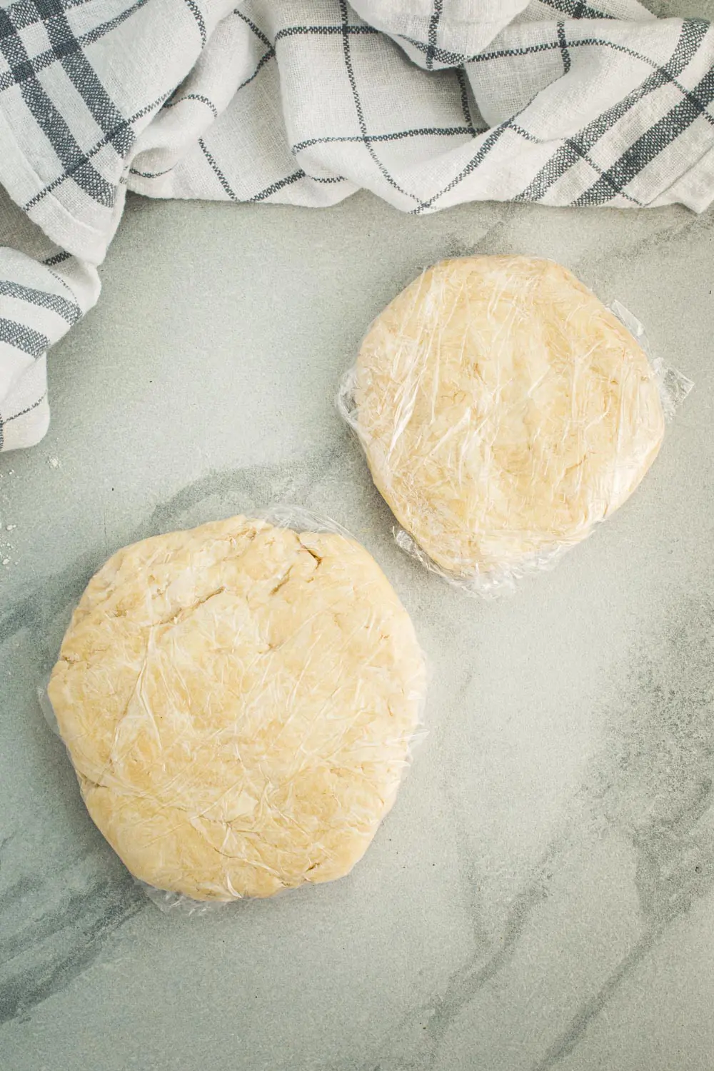 Flaky pie crust dough wrapped in plastic wrap.
