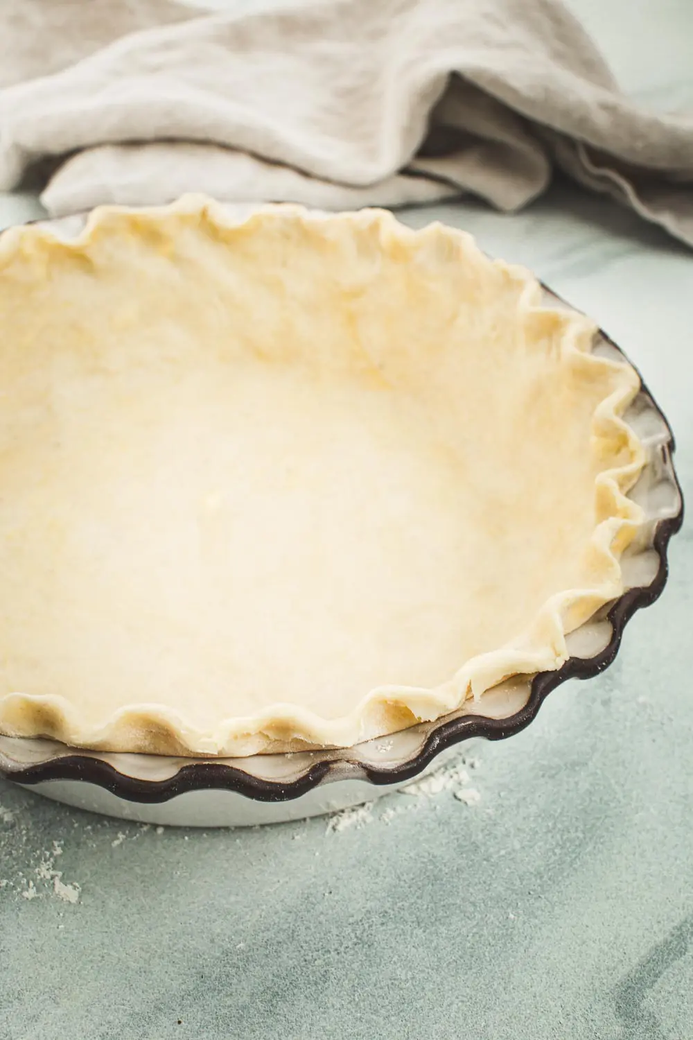 Homemade flaky pie crust set up in a white pie dish.